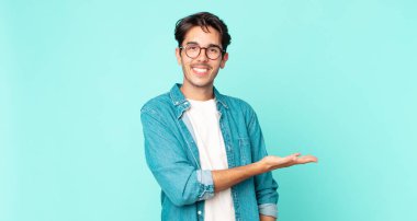 İspanyol yakışıklı adam neşeyle gülümsüyor, kendini mutlu hissediyor ve fotokopi uzayda avucunun içinde bir konsept gösteriyor.