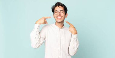 İspanyol yakışıklı adam kendine güvenerek gülümsüyor. Geniş gülümseme, pozitif, rahat, tatmin olmuş tavır.