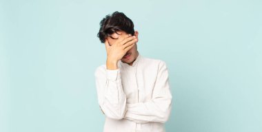 İspanyol yakışıklı adam stresli, utanmış ya da üzgün görünüyor, baş ağrısı var, yüzünü eliyle kapatıyor.