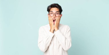 İspanyol yakışıklı adam şok olmuş ve korkmuş hissediyor, ağzı açık ve elleri yanaklarında korkmuş görünüyor.