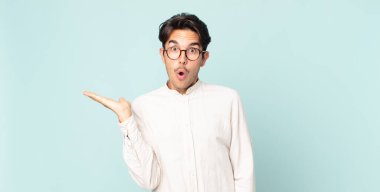 İspanyol yakışıklı adam şaşırmış ve şoka uğramış görünüyor, çenesi düşmüş, bir objeyi elinde açık bir elle tutuyor.