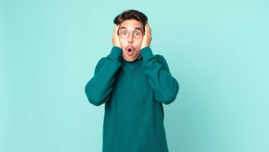 İspanyol yakışıklı adam hoş olmayan bir şekilde şok olmuş, korkmuş ya da endişeli görünüyor ağzı sonuna kadar açık ve iki kulağını da elleriyle kapatıyor.