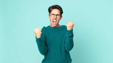 İspanyol yakışıklı bir adam sinirli bir ifadeyle agresif bir şekilde bağırıyor ya da yumruklarıyla başarıyı kutluyor.