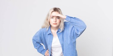 Güzel albino kadın şaşkın ve şaşkın bakıyor, el üstünde uzak bakıyor, izliyor ya da arıyor