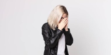 Güzel albino kadın üzgün, hayal kırıklığına uğramış bir bakışla gözlerini kapatıyor, ağlıyor, yan gözle bakıyor.