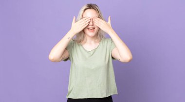 Güzel albino kadın gülümsüyor ve mutlu hissediyor, iki eliyle gözlerini kapatıyor ve inanılmaz bir sürpriz bekliyor.