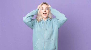 Güzel albino kadın, el ele tutuşuyor, ağzı açık, son derece şanslı, şaşırmış, heyecanlı ve mutlu.