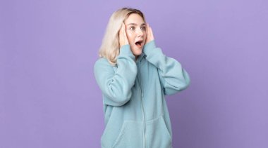 Sevimli albino kadın mutlu, heyecanlı ve şaşırmış hissediyor, iki eli yüzü yana bakıyor