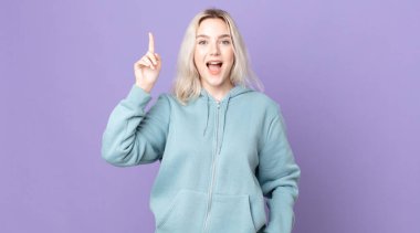 Güzel albino kadın bir fikri fark ettikten sonra mutlu ve heyecanlı bir dahi gibi hissediyor, neşeli bir şekilde parmağını kaldırıyor, eureka!