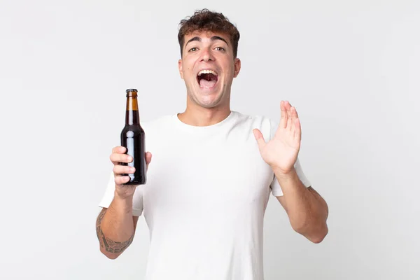 若いハンサムな男はビール瓶を持っている信じられないほどの何かに幸せと驚き — ストック写真