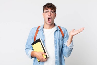 Genç, yakışıklı adam şaşırmış ve şok olmuş görünüyor. Çenesi düşmüş, elinde bir nesne var. Üniversite öğrencisi konsepti