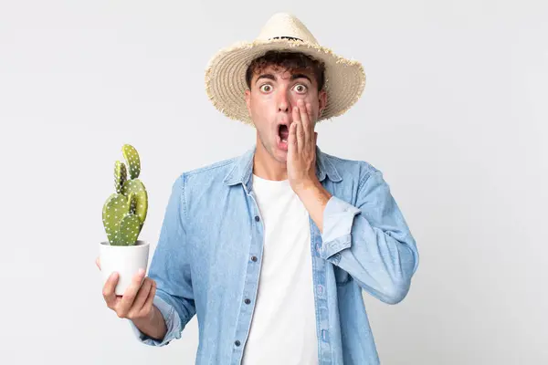Young Handsome Man Feeling Shocked Scared Farmer Holding Decorative Cactus — Stock Photo, Image