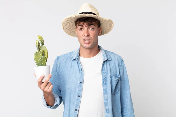 Joven Hombre Guapo Sintiéndose Desconcertado Confundido Agricultor Que Posee Cactus —  Fotos de Stock