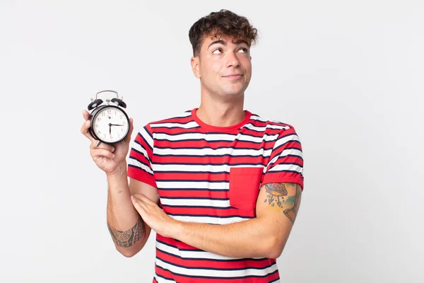 Young Handsome Man Shrugging Feeling Confused Uncertain Holding Alarm Clock — Stock Photo, Image