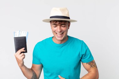 Genç yakışıklı bir adam komik bir şakaya yüksek sesle gülüyor. Elinde pasaportu olan bir yolcu.