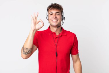 Genç yakışıklı adam kendini mutlu hissediyor, iyi bir jestle onaylıyor. tele pazarlamacı kavramı