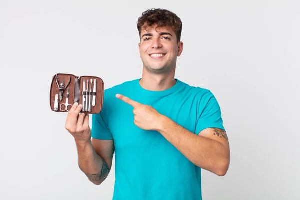 Joven Hombre Guapo Sonriendo Alegremente Sintiéndose Feliz Señalando Lado Sosteniendo —  Fotos de Stock