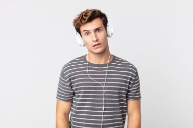 Genç yakışıklı adam şaşkın ve şaşkın hissediyor. müzik konseptini dinlemek