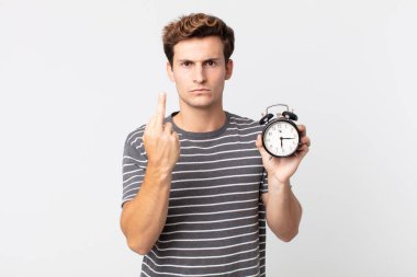 Genç ve yakışıklı bir adam kızgın, sinirli, asi ve saldırgan ve elinde çalar saat tutuyor.