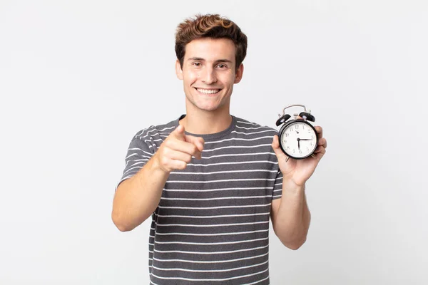Young Handsome Man Pointing Camera Choosing You Holding Alarm Clock — Stock Photo, Image