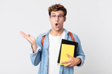 Genç, yakışıklı adam şaşırmış ve şok olmuş görünüyor. Çenesi düşmüş, elinde bir nesne var. Üniversite öğrencisi konsepti
