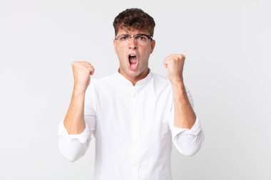 Genç yakışıklı bir adam sinirli bir ifadeyle ya da yumruklarıyla başarıyı kutlarken agresif bir şekilde bağırıyor.