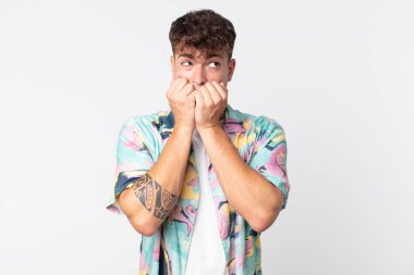 Genç yakışıklı adam endişeli, endişeli, stresli ve korkmuş görünüyor, tırnaklarını yiyor ve yanal fotokopi alanı arıyor.