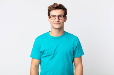 Genç yakışıklı adam pozitif ve kendinden emin gülümsüyor. Tatmin olmuş, arkadaş canlısı ve mutlu görünüyor.