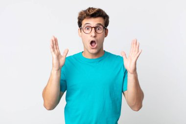 Genç yakışıklı adam şok olmuş ve şaşkın bakıyor, inanılmaz bir şey fark ettiğinde çenesi şaşkın şaşkın