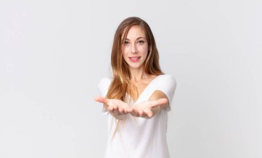 Oldukça zayıf bir kadın mutlu bir şekilde gülümsüyor, arkadaş canlısı, kendine güvenen, olumlu bakışlı, bir nesne ya da konsept sunan ve gösteren