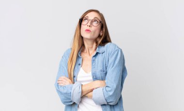 Oldukça zayıf bir kadın omuz silkiyor, kafası karışık ve kararsız, kolları bağlı ve şaşkın görünüyor.