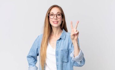 Çok zayıf bir kadın gülümsüyor ve arkadaş canlısı görünüyor. İki ya da iki numarayı gösteriyor. Elleri önde, geri sayıyor.