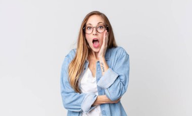 Oldukça ince bir kadın şok ve inanmazlık içinde, elleri yanağında ve kolları çaprazlanmış, sersemlemiş ve şaşırmış hissediyor.