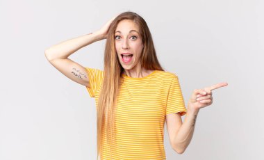 Oldukça zayıf bir kadın gülüyor, mutlu, pozitif ve şaşırmış görünüyor, yanal fotokopi alanını işaret eden harika bir fikrin farkına varıyor.