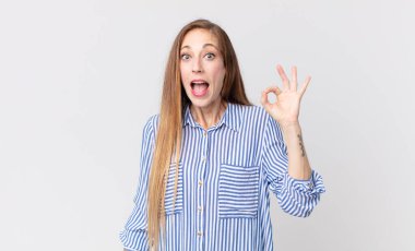 Oldukça zayıf bir kadın kendini başarılı ve tatmin olmuş hissediyor, ağzı açık gülümsüyor, elle işaret veriyor.