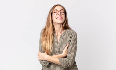 Oldukça zayıf bir kadın kollarını kavuşturup mutlu bir şekilde gülüyor, rahat, pozitif ve tatmin edici bir pozla.