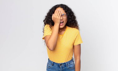 Güzel İspanyol kadın uykulu görünüyor, sıkılmış ve esniyor, baş ağrısı ve yüzünün yarısını kaplayan bir eliyle