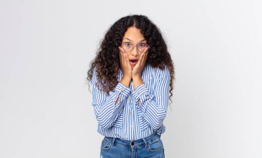 Güzel İspanyol kadın şok olmuş ve korkmuş hissediyor, ağzı açık ve elleri yanaklarında korkmuş görünüyor.