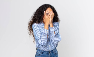 Güzel İspanyol bir kadın korkmuş ya da utanmış hissediyor. Gözleri yarı kapalı ya da elleri kapalı gözetliyor.