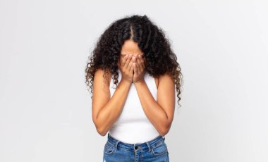 Güzel İspanyol bir kadın üzgün, hayal kırıklığına uğramış, gergin ve depresif, iki eliyle yüzünü kaplayan, ağlayan