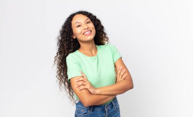 Güzel İspanyol kadın kollarını kavuşturup mutlu bir şekilde gülüyor, rahat, pozitif ve tatmin edici bir pozla.