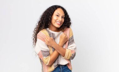 Güzel İspanyol kadın neşeli bir şekilde gülümsüyor ve kutluyor, yumruklarını sıkıp kollarını kavuşturuyor, mutlu ve pozitif hissediyor.