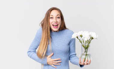 İnce, güzel bir kadın komik bir şakaya yüksek sesle gülüyor ve elinde Flowers 'la vazo tutuyor.