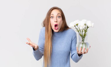 Sıska, güzel bir kadın çok şaşırmış ve elinde Flowers 'la vazo tutuyor.