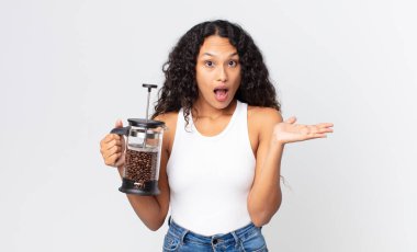 İspanyol güzel kadın şaşırmış ve şok olmuş görünüyor, çenesi düşmüş, elinde elle kahve makinesiyle bir nesne tutuyor.