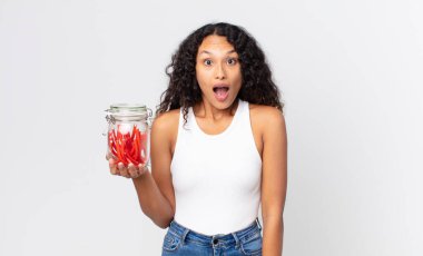 İspanyol güzel kadın şok olmuş ya da şaşırmış görünüyor ve elinde kırmızı meyankökü jelibonu tutuyor.