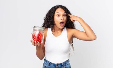 İspanyol güzel kadın şaşırmış görünüyor, yeni bir düşünce, fikir veya konsept fark ediyor ve elinde kırmızı meyankökü jelibonu tutuyor.