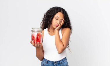 İspanyol güzel kadın sıkılmış, hayal kırıklığına uğramış ve uykulu hissediyor yorucu ve elinde kırmızı meyankökü jelibonuyla