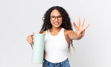 İspanyol güzel kadın gülümsüyor ve arkadaş canlısı görünüyor, dört numarayı gösteriyor ve elinde kahve termosu var.