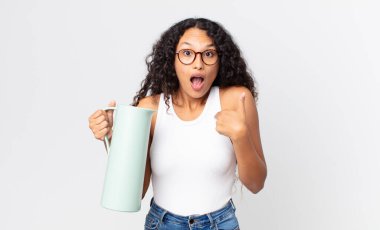 İspanyol güzel bir kadın ağzı açık, elinde kahve termosuyla şaşkın ve şaşırmış görünüyor.